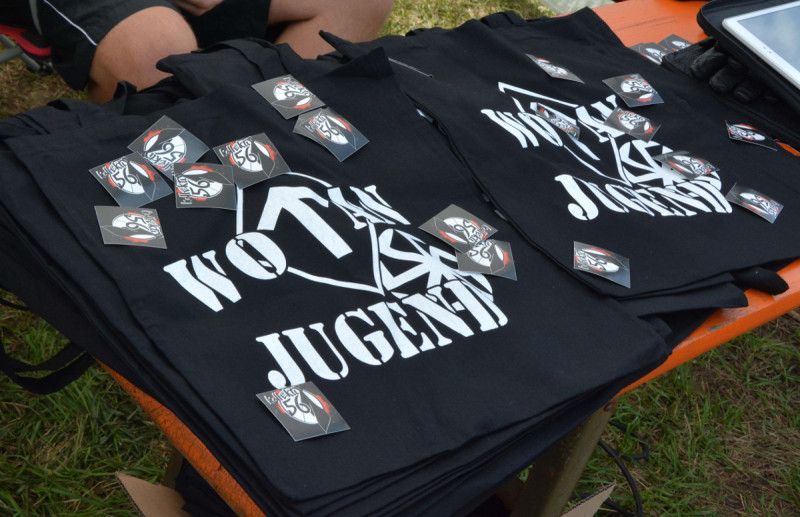 Die Wotan Jugend ist ein internationales Neonazi-Netzwerk mit Aktivist_innen in Deutschland. Kennzeichen der Wotan-Jugend ist die Tyr-Rune in der Raute. Das Bild zeigt das Angebot für Bekleidung der Wotan-Jugend auf einem Neonazi-Konzert 2017 in Thüringen.