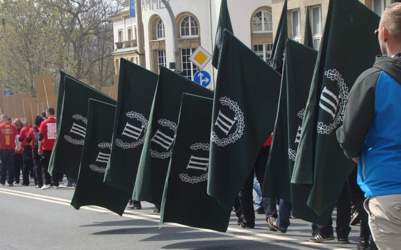 Die Aufmärsche der Partei Der III. Weg sind geprägt von den Farben Schwarz-Weiß-Rot, voranschreitenden Trommlern, Fackelformationen und Fahnenblöcken.