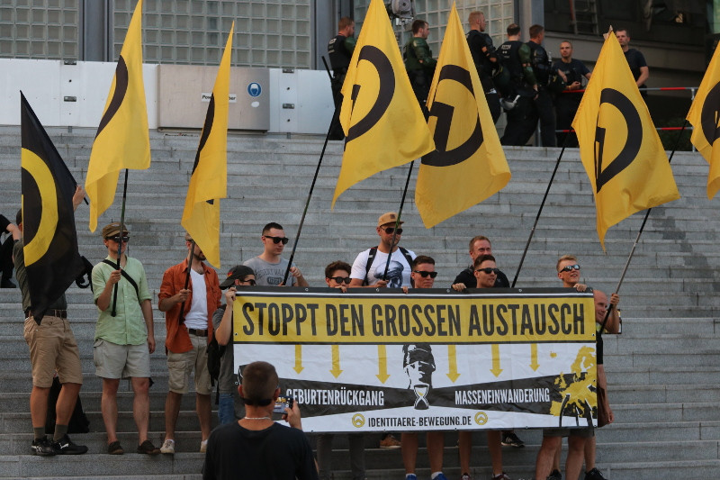 Aufstellung von Aktivist_innen der Identitären Bewegung für den Fotografen vor einer menschenleeren Treppe am Berliner Hauptbahnhof.