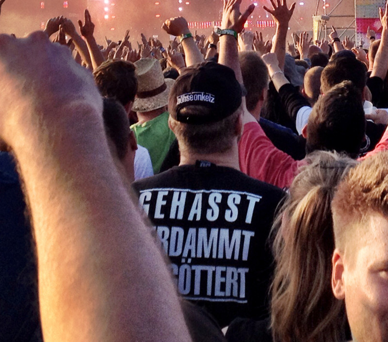 Das Foto zeigt kein RechtsRock-Konzert, sondern ein Böhse-Onkelz-Konzert im Jahr 2014. Der Ausspruch »Gehasst Verdammt Vergöttert« wurde von den Böhsen Onkelz geprägt und kleidet Generationen von Deutschrock-Fans. Auch von Neonazis wird er häufig zitiert, beispielsweise in Einträgen unter »Lebensmotto« in Sozialen Netzwerken. Auch existieren in der extrem Rechten zahlreiche Abwandlung dieses Spruchs.
