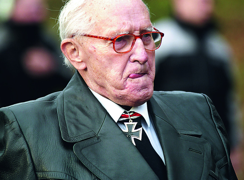 Altnazi auf einem Aufmarsch in Hessen 2003 mit dem Orden »Ritterkreuz des Eisernen Kreuzes«, der im Nationalsozialismus verliehen wurde. Das öffentliche Zeigen des Ordens ist aufgrund des darin enthaltenen Hakenkreuzes verboten. Die Veröffentlichung dieses Fotos brachte den Träger eine Strafanzeige ein, der Orden wurde polizeilich beschlagnahmt.
