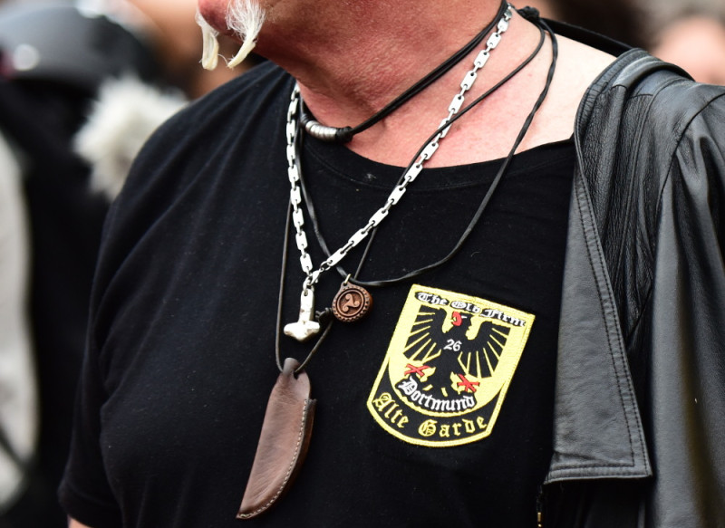 Die gerundete Triskele als Halskette zwischen Thorshammer und dem Aufdruck »The Old Firm 26 Dortmund Alte Garde«. Der Zahlencode 26 steht für die Buchstaben B und F und für die Neonazigruppe Borussenfront aus dem Raum Dortmund