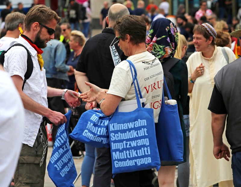 Rechte Themen und Kampfbegriffe werden verschwörungsideologisch verbunden, in diesem Fall: »Klimawahn«, »Schuldkult«, »Impfzwang«, »Multikulti« und »Gendergaga«. Für manche Aktivist*innen ist dies ein einträgliches Geschäft. Bei der Kundgebung der extrem rechten Gruppierung Patriotic Opposition Europe und der Berliner »Corona Rebellen« am 4. Juli 2020 auf dem Berliner Alexanderplatz wurden die abgebildeten Stoffbeutel massenhaft verkauft.