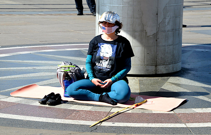 Teilnehmerin einer »Ignorance Meditation« (siehe Ken Jebsen) auf einer »Hygienedemo« im Mai 2020 in Berlin. Der Mundschutz mit der US-amerikanischen Flagge und das Shirt-Motiv sind eine Solidaritätsbekundung für Julian Assange, dem ehemaligen Sprecher der Enthüllungsplattform WikiLeaks, der in den USA wegen der Veröffentlichung geheimer Dokumente angeklagt ist.