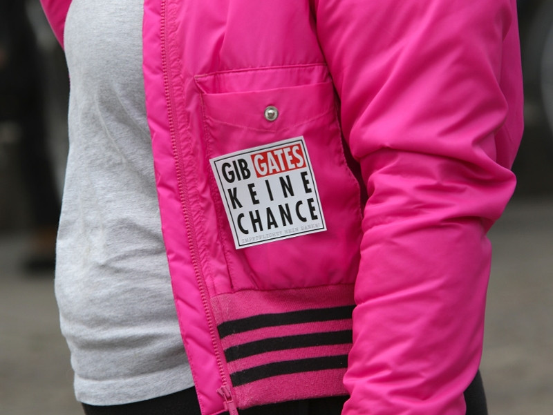 »Gib Gates keine Chance« als Abwandlung des Logos der Anti-AIDS-Kampagne ist eines der am häufigsten gezeigten Symbole auf Versammlungen verschwörungsideologischer Kreise.
Der Slogan entstand als Reaktion auf die Aktion #solidaritypledge der Bill-und-Melinda-Gates-Stiftung. Mit dieser sollte in Zeiten des Coronavirus in Sozialen Netzwerken gesellschaftliche Solidarität sichtbar gemacht werden. Die Aktion #solidaritypledge nahm der verschwörungsideologische YouTuber Oliver Janich zum Anlass, ein vermeintliches »Aufklärungsvideo« über die Stiftung zu drehen. Damit verband er die Aufforderung, den Hashtag #solidaritypledge durch massenhafte Nutzung zu übernehmen und umzudeuten. Hashtags sind Schlagworte, die mit dem Doppelkreuz-Symbol markiert sind und helfen, Themen in sozialen Medien leichter zu finden. Die »feindliche Übernahme« des Hashtags #solidaritypledge bewirkt, dass Internet-Nutzer*innen bei der Suche nach der Kampagne vermehrt die Inhalte der Gegenkampagne unter dem Slogan »Gib Gates keine Chance« finden. Die Idee zu dem Slogan »Gib Gates keine Chance« kam vom rechtsoffenen Blogger Mirò Wolsfeld (UNBLOGD).